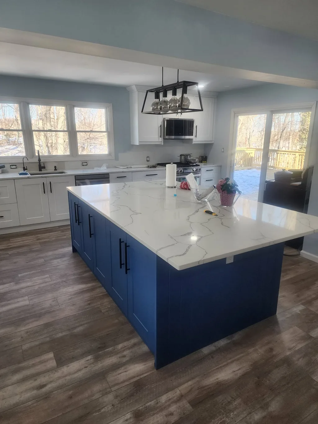 Kitchen remodel by Parisi Home Improvement with a navy island, white shaker cabinets and a marble-look countertop